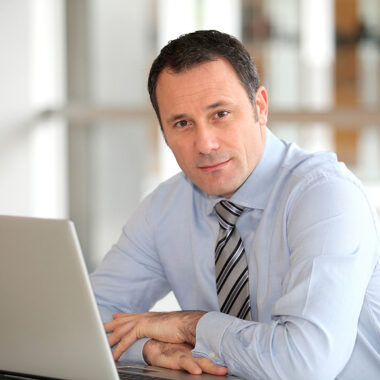 Man wearing a dress shirt and tie working at his laptop